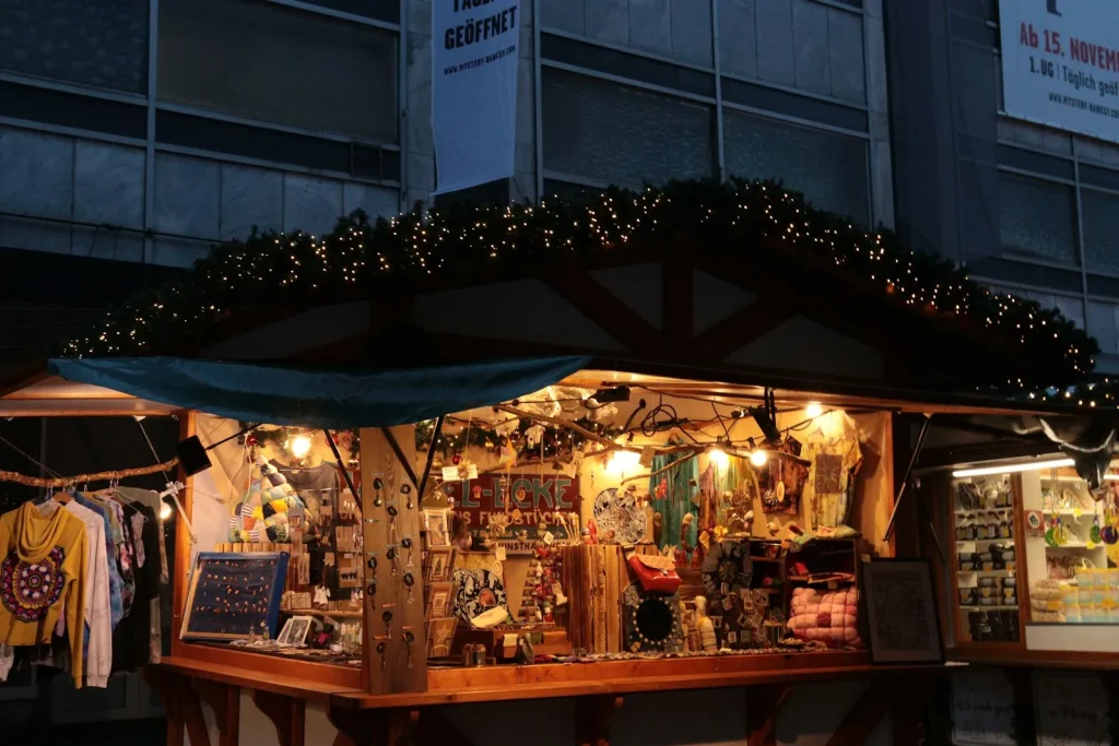 Vendre ses créations sur un marché de Noël : le stand qui vend, et qui te fait retrouver après 1 Un chalet de marché de Noël illuminé de guirlandes, avec des créations artisanales exposées