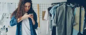 Une créatrice photographie ses vêtements avec son téléphone dans son atelier