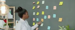 Une entrepreneuse organise les post-it de sa stratégie de communication sur un mur