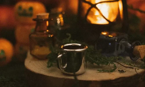 Citrouilles, lanterne allumée et petites fioles sur un rondin de bois, ambiance Halloween