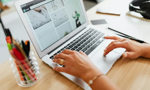 Mains sur un ordinateur portable affichant un site web, sur un bureau en bois